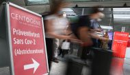 Travellers rush past the entry of Germany's first walk-through the coronavirus disease (COVID-19) test center which is opened by diagnostics provider Centogene in cooperation with air carrier Lufthansa and Fraport at the airport in Frankfurt, Germany June