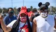 A couple waits in line to enter Downtown Disney in Anaheim, California on July 9, 2020, the first day the outdoor shopping and dining complex has been open to the public since it closed in mid-March amid the COVID-19 pandemic. (AFP / Robyn Beck)