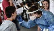A public health worker collects a swab sample from a boy to test for the COVID-19, the novel coronavirus, at the Greek-Bulgarian border crossing in Promachonas on July 10, 2020. / AFP / Sakis MITROLIDIS
