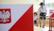 A man in traditional clothes arrives with his young to vote on July 12, 2020 in Zab near Zakopane, during the second round of Poland's presidential election. AFP / BARTOSZ SIEDLIK