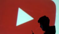 FILE PHOTO: A silhouette of a mobile user is seen next to a screen projection of Youtube logo in this picture illustration taken March 28, 2018. REUTERS/Dado Ruvic/File Photo
