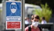 A man wearing a protective face mask due to the COVID-19 coronavirus pandemic, walks next to a mandatory wearing mask sign in front of a shop in a pedestrian street in Lille on July 20, 2020, as masks become mandatory in all indoor public spaces. AFP / DE