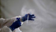 A laboratory worker cleans the tube containing a sample from a customer at the Certus Lab's COVID-19 drive-thru test centre at the parking lot of the Caliente multipurpose complex in Tijuana, Baja California State, Mexico, on July 21, 2020 amid the novel 