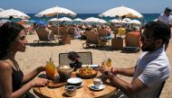 FILE PHOTO: A woman and a man sit in a bar as they enjoy the sunny weather at Barceloneta beach, after Catalonia's regional authorities and the city council announced restrictions to contain the spread of the coronavirus disease (COVID-19) in Barcelona, S