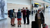A man carries a luggage as reporters wearing face masks speak to travellers arriving from MADRID at the Terminal 5 at Heathrow Airport, as the spread of the?coronavirus?disease (COVID-19) continues, in London, Britain, July 26, 2020. REUTERS/Henry Nicholl