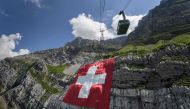 A picture taken on on July 31, 2020 near Schwagalp, eastern Switzerland, shows a huge 6,400 square meters Swiss flag hanging on the rock face of mountain Saentis on the eve of Swiss national day. / AFP / Fabrice COFFRINI