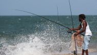Harold Dixon fishes near crashing waves along the jetty as Tropical Storm Isaias approaches on August 01, 2020 in Fort Pierce, Florida.  . Joe Raedle/AFP