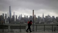 A man walks into heavy wind and rain along the waterfront of the Hudson River in front of the New York City skyline during Tropical Storm Isaias in Weehawken, New Jersey, U.S., August 4, 2020. REUTERS/Mike Segar