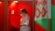 A woman wearing a protective face mask stands inside a voting booth at a polling station during the presidential election in Minsk, Belarus August 9, 2020. REUTERS/Vasily Fedosenko