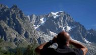 A security officer looks through binoculars at the Planpincieux glacier in Courmayeur village, Val Ferret, northwestern Italy on August 8, 2020. Several dozen people have been evacuated in northwestern Italy as a huge chunk of a glacier in the Mont Blanc 