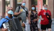 An accordion player wears a protective facemask as he plays on a street in Antwerp on August 6, 2020, as authorities impose additional measures to attempt to curb the spread of the COVID-19 caused by the novel coronavirus