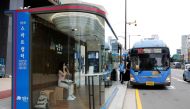 A woman wears a mask inside a glass-covered bus stop in which a thermal imaging camera, UV sterilizer, air conditioner, CCTV and digital signage are set, to avoid the spread of COVID-19 in Seoul, South Korea, August 14, 2020. REUTERS/Heo Ran