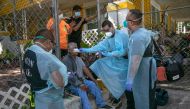 An EMS medic checks the temperature of a possible Covid-9 patient before transporting him to the hospital on August 13, 2020 in Houston, Texas. Several of the man's family members had also tested positive. The Latino community in Houston has been especial