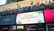 A tourist takes a selfie video underneath a billboard welcoming people back to NYC in Times Square on August 16, 2020 in New York. / AFP / Bryan R. Smith