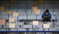 A woman wearing a protective face mask and a face shield holds social distancing as a measure to contain the spread of the coronavirus disease (COVID-19) before taking the entrance exam for Mexico's National Autonomous University in the stands of Universi