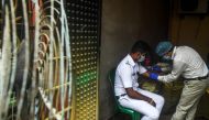 A health worker (R) collects a blood sample from a police official for antibodies test of COVID-19 coronavirus, in Kolkata on August 23, 2020. / AFP / Dibyangshu SARKAR