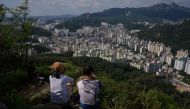 Hikers sit at a viewpoint overlooking the Seoul city skyline on August 23, 2020. South Korea ramped up coronavirus restrictions on August 23 to try to contain a growing outbreak, as many countries around the world battled worrying surges in infections. / 