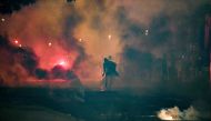 A man stands in tear gas smokes fired by French anti-riot policemen escorting Paris Saint-Germain (PSG) supporters around the Parc des Princes stadium on August 23, 2020. AFP / Alain JOCARD
