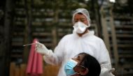 :A health worker, wearing a protective suit and a face mask, prepares to administer a nasal swab to a patient at a testing site for the coronavirus disease (COVID-19) installed at the Bassin de la Villette in Paris, France, August 25, 2020. REUTERS/Gonzal