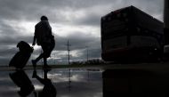 A woman rolls a suitcase as she walks to board a bus for evacuation before the arrival of hurricane Laura in Lake Charles, Louisiana on August 25, 2020 amid the coronavirus pandemic. / AFP / Andrew CABALLERO-REYNOLDS
