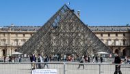 People wearing face masks walk in front of the Louvre Pyramid (Pyramide du Louvre) designed by Ieoh Ming Pei, at the Cour Napoleon, in Paris, on August 27, 2020.  AFP / Ludovic MARIN / 