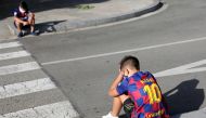 Boys sit on a street as they wait for FC Barcelona's squad to arrive for coronavirus disease (COVID-19) test, ahead of the resumption of training on August 31, in Barcelona, Spain August 30, 2020. REUTERS/Nacho Doce