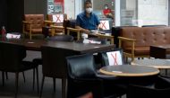 A man wearing a protective face mask sits as signs are attached to chairs to keep social distancing at a cafe, amid the coronavirus disease (COVID-19) pandemic in Seoul, South Korea, August 27, 2020. REUTERS/Kim Hong-Ji