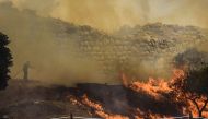 A firefighter works to put out a wildfire near the archaeological site of Mycenae in the northeastern Peloponnese, on August 30, 2020. A wildfire broke out near the ruins of the Bronze Age stronghold of Mycenae in Greece on August 30, prompting the evacua