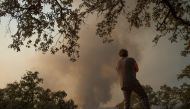 A resident observes a wildfire raging near El Buitron in Huelva on August 30, 2020. At least 3,200 people were evacuated because of a fire that has already ravaged some 10,000 hectares in the southwestern Spanish province of Huelva and which remains activ