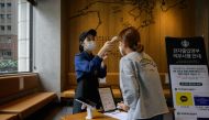 A customer has her temperature checked as a preventative measure against the COVID-19 coronavirus inside a cafe in Seoul on August 31, 2020. / AFP / Ed JONES