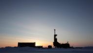 FILE PHOTO: The sun sets behind an oil drilling rig in Prudhoe Bay, Alaska on March 17, 2011. REUTERS/Lucas Jackson/File Photo - RC1C644EA560
