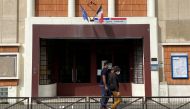 People wearing protective face masks walk past the College Valmy school in Paris, France, September 10, 2020. REUTERS/Rali Benallou
