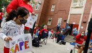 A parent and a child carry signs to protest the opening of schools, as teachers work outside their school building for safety reasons, following the outbreak of the coronavirus disease (COVID-19) in the Brooklyn borough of New York City, U.S., September 1