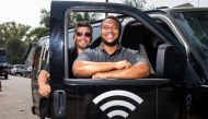 Roman Reyna (L) owner of JFK transportation and Kevin Watson (R), president of JFK transportation, pose with one of their company vans equipped as a mobile Wifi Hotspot to help students access internet to remotely attend their classes, September 16, 2020,