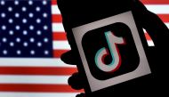 :(FILES) In this file photo illustration taken on August 3, 2020, the social media application logo, TikTok is displayed on the screen of an iPhone on an US flag as the background in Arlington, Virginia. President Donald Trump on September 21, 2020 threw 