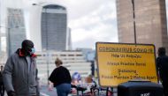 A pedestrian wears a facemask due to the novel coronavirus COVID-19 pandemic on London Bridge in central London on September 25, 2020. Britain's Prime Minister Boris Johnson, this week announced a host of new restrictions, including early closing times fo