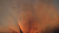 A helicopter is backlit by the sun setting as it drops water over the Bothe-Napa Valley State Park alight from the Glass Fire in Calistoga, California, U.S. October 3, 2020. REUTERS/Adrees Latif