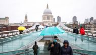 People walk across Millennium Bridge during rainy weather, in LONDON, Britain, October 4, 2020. REUTERS/Henry Nicholls
