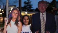 A supporter stands in between cardboard cutouts of First Lady Melania Trump and U.S. President Donald Trump, outside of the Walter Reed National Military Medical Center in Bethesda, Maryland, U.S. October 4, 2020. REUTERS/Cheriss May
