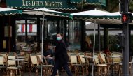 A woman wearing a protective face mask walks past the cafe and restaurant Les Deux Magots in Paris, during the announcement of new Covid restrictions by Paris authorities as the coronavirus disease (COVID-19) outbreak continues in France, October 5, 2020.