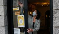 A shopkeeper wearing a protective face mask closes one of her shop doors as the National Public Health Emergency Team (NPHET) announced recommendations that the government implement the highest level of COVID-19 restrictions to Level 5, amid the coronavir