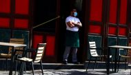 A waiter wearing a protective face mask waits for customers in his terrace amid the outbreak of the coronavirus disease (COVID-19), in Madrid, Spain October 1, 2020. REUTERS/Sergio Perez/File Photo/File Photo