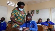 School teacher Elizabeth Nyabwa attends to a student inside a classroom at the Olympic Primary School during the partial reopening of schools, after the government scrapped plans to cancel the academic year due to the coronavirus disease (COVID-19) pandem