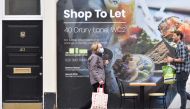 A pedestrian wearing a face mask as a precaution against the transmission of the novel coronavirus walks past a boarded up shop front which is to let in central London on October 13, 2020.  AFP / JUSTIN TALLIS