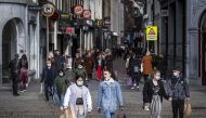 People wearing face masks walk on a shopping street in the center of Amsterdam on October 11, 2020. The Dutch government is expected to take new measures to halt the spread the Covid-19 disease caused by the novel coronavirus. - / AFP / ANP / Ramon van Fl