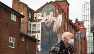 A man wearing a facemask walks past a mural painted as part of the Cities of Hope festival in 2016 and highlighting the effects of mental health, in Ancoats, northern Manchester on October 16, 2020, as the number of cases of the novel coronavirus COVID-19