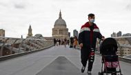A man pushing a pram crosses Millennium Bridge in view of St Paul's Cathedral as the coronavirus disease (COVID-19) outbreak continues in London, Britain October 18, 2020. Reuters/Simon Dawson
 