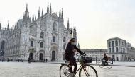 A person wearing a protective mask rides a bicycle at Duomo Square, in the northern Lombardy region of Italy, after the government brings in new restrictive measures due to a rise in the number of the coronavirus disease (COVID-19) infections, in Milan, I