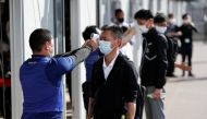 Officials check body temperature of people acting as spectators during screening measures test, hosted by Tokyo Organising Committee of the Olympic and Paralympic Games, ahead of the summer games that have been postponed to 2021 due to the coronavirus dis