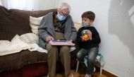 Florentina Martin, a 99-year-old woman who survived coronavirus disease (COVID-19), plays a digital puzzle with her great-grandson Pedro Valle at her home in Pinto, near Madrid, Spain, October 20, 2020. Picture taken October 20, 2020. Reuters/Sergio Perez